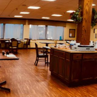 A spacious dining area featuring wooden furniture, ample natural light from large windows, and a warm ambiance.