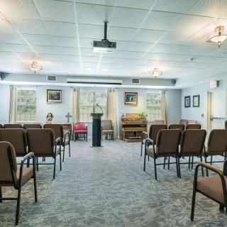 An interior view of a small chapel with seating arranged around a central podium.