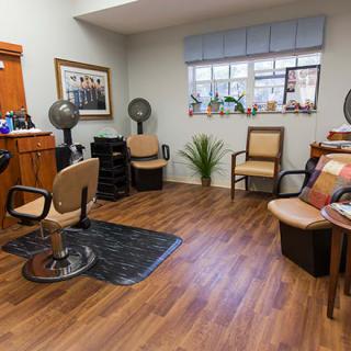 Interior view of a hair salon with chairs, mirrors, and wooden flooring.