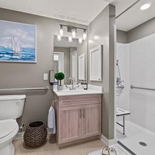 A modern bathroom with a shower, toilet, and sink, featuring contemporary decor and artwork.
