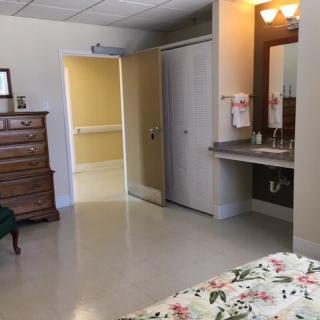A well-organized room with a bed, dresser, and sink, typical of a hospital or care facility.