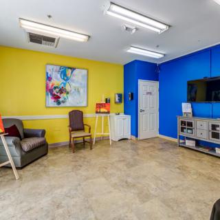A vibrant waiting room with colorful walls, featuring a television and seating area.