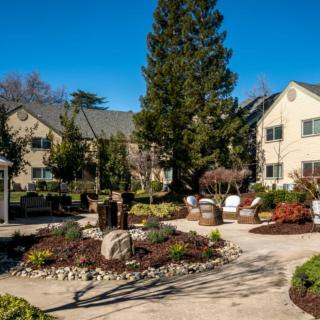 A well-maintained garden with a pathway and benches in front of a residential building.