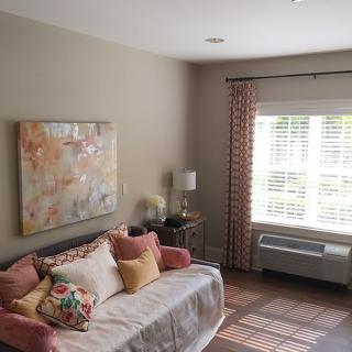 A cozy living room with a sofa, colorful pillows, and abstract artwork on the wall.