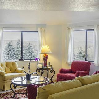 A cozy living room with colorful furniture and large windows allowing natural light.