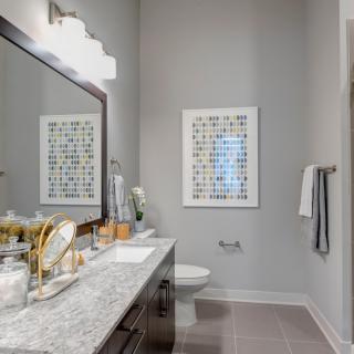 A modern bathroom featuring a large mirror, stylish countertop with accessories, and framed wall art.