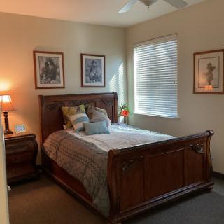 A cozy, well-decorated bedroom featuring a wooden bed, bedside lamp, and framed artwork.