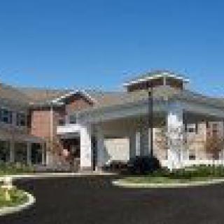 A modern residential building with a covered entrance and landscaped surroundings.