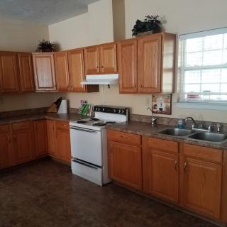 A spacious kitchen with wooden cabinets and a white stove.