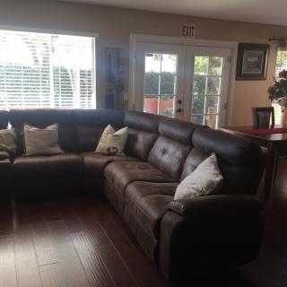 A cozy living room featuring a large sectional sofa with pillows and ample natural light coming through the windows.