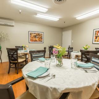 A cozy dining room setup featuring elegantly arranged tables with floral centerpieces.