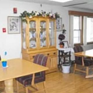 A cozy dining area featuring tables, chairs, and a wooden cabinet with decorative items.