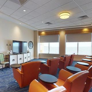 A well-lit room with comfortable seating and a television, featuring large windows.