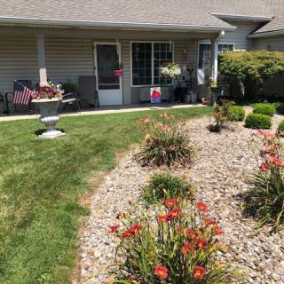 A well-maintained backyard garden with various flowers, rocks, and a cozy patio area.