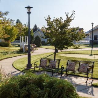 A serene park setting with benches, a pathway, trees, and a gazebo.