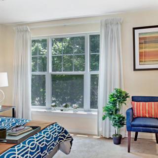 A cozy bedroom with a large window, elegant curtains, and vibrant decor.