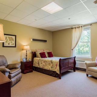 A cozy bedroom with a comfortable bed, armchairs, and warm lighting.