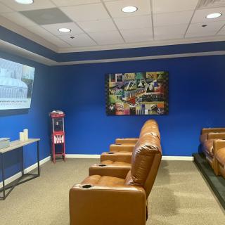 A cozy home theater room with leather seating, a projector screen, and a popcorn machine against blue walls.