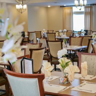 An elegantly arranged dining area with neatly set tables and floral decorations.