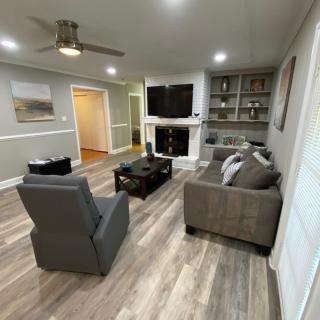 A modern living room with a gray sofa, armchair, and fireplace, featuring wood flooring and built-in shelves.