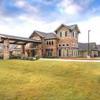 A large, modern house with a well-maintained lawn under a partly cloudy sky.