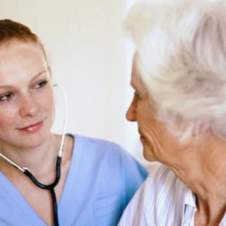 A nurse is attentively listening to an elderly patient's concerns during a medical check-up.