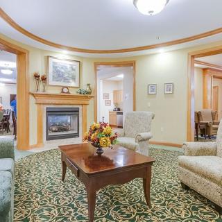 A cozy, traditionally decorated living room featuring a fireplace, armchairs, and a carpet with intricate patterns.