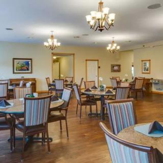 A spacious and elegantly designed dining room with chandeliers, round tables, and comfortable chairs.