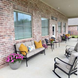 A cozy patio area with comfortable seating and decorative cushions, set against a brick wall with large windows.
