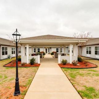 A symmetrical view of a building entrance with a pathway and lamp post.