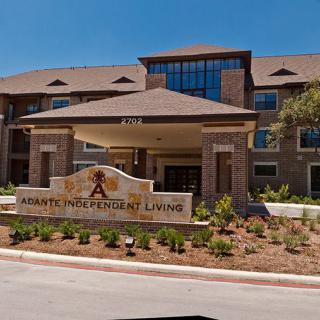 Entrance to a residential building with prominent signage and landscaping.