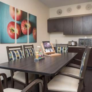 A modern dining area featuring a dark wood table, matching chairs, and vibrant artwork on the wall.