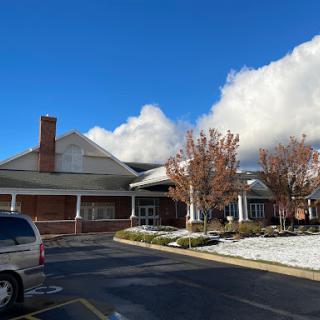A cozy building under a bright blue sky with clouds, surrounded by a hint of snowfall.