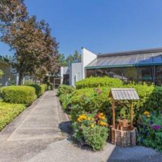 A well-maintained building surrounded by lush gardens and a clear blue sky.