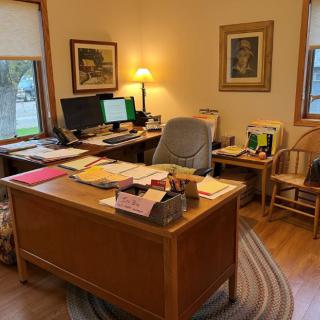 A tidy home office featuring a wooden desk with papers, a computer setup, and a comfortable chair.
