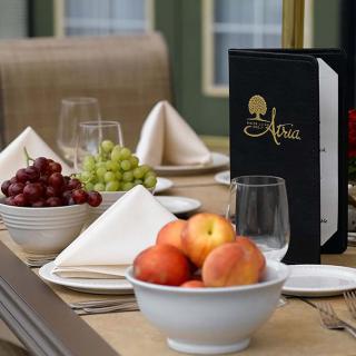 A beautifully set dining table with bowls of grapes and peaches, accompanied by a menu in an elegant restaurant setting.