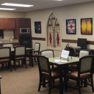 A multipurpose room featuring a kitchen, dining tables, and a computer station.