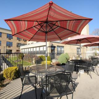 A sunny outdoor patio area with striped umbrellas providing shade over tables and chairs.