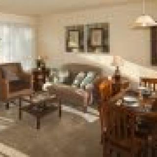 A cozy living room with a sofa, coffee table, and dining area.