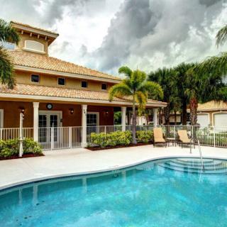 A tropical vacation home with a swimming pool and palm trees.
