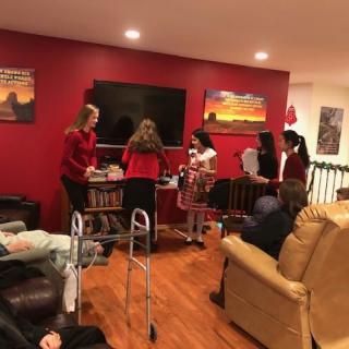 A group of people gathered in a cozy living room with red walls and a television.