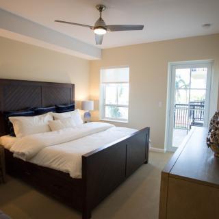 A modern bedroom with a double bed, ceiling fan, and ample natural light.