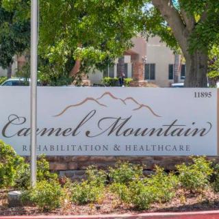 A sign for Carmel Mountain Rehabilitation & Healthcare surrounded by trees and greenery.