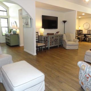 A modern living room with hardwood flooring, featuring comfortable seating and a mounted TV.