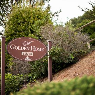 A sign for a place called 'Golden Home' surrounded by greenery.