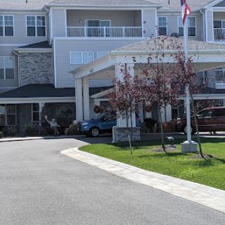 A welcoming entrance to a residential building with landscaped grounds and a prominent flag.