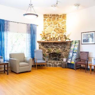 A cozy and inviting living room with a stone fireplace, comfortable chairs, and plenty of natural light.
