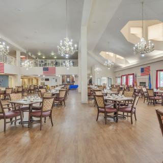 A spacious dining hall with elegant chandeliers and neatly arranged tables and chairs.