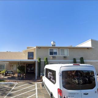 A white van parked in front of a hotel building with a clear blue sky.