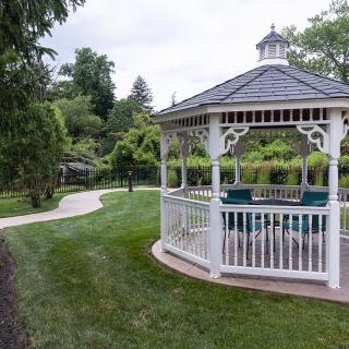A scenic garden featuring a white gazebo and winding pathway surrounded by lush greenery.